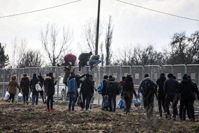 Des migrant·e·s sautent des barrières érigées par l'armée turque près du point de passage de Pazarkule, le 4 mars 2020 (Ozan Kozé/AFP).